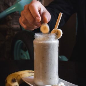 person putting sliced banana fruit on top of jar